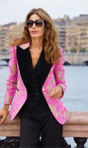 Una mujer con una chaqueta jacquard de un botón rebecka apoyada en una barandilla.