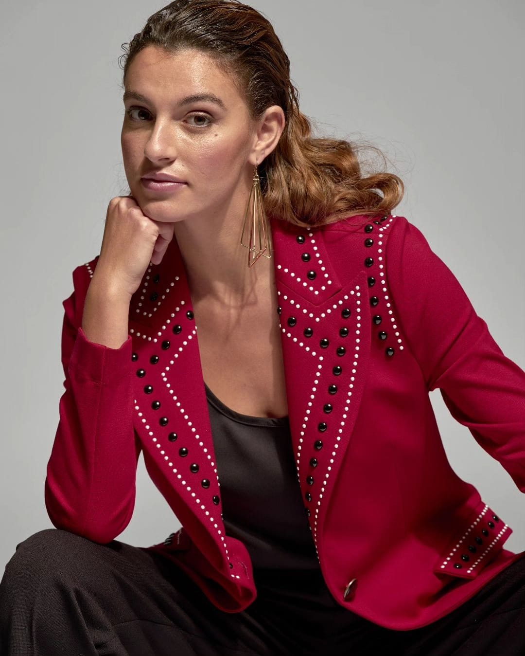 Una mujer con una chaqueta de MOSKADA en punto con detalles, llevando pantalones negros.