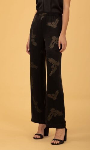 El modelo lleva un pantalón en tejido fluido negro con estampado dorado.