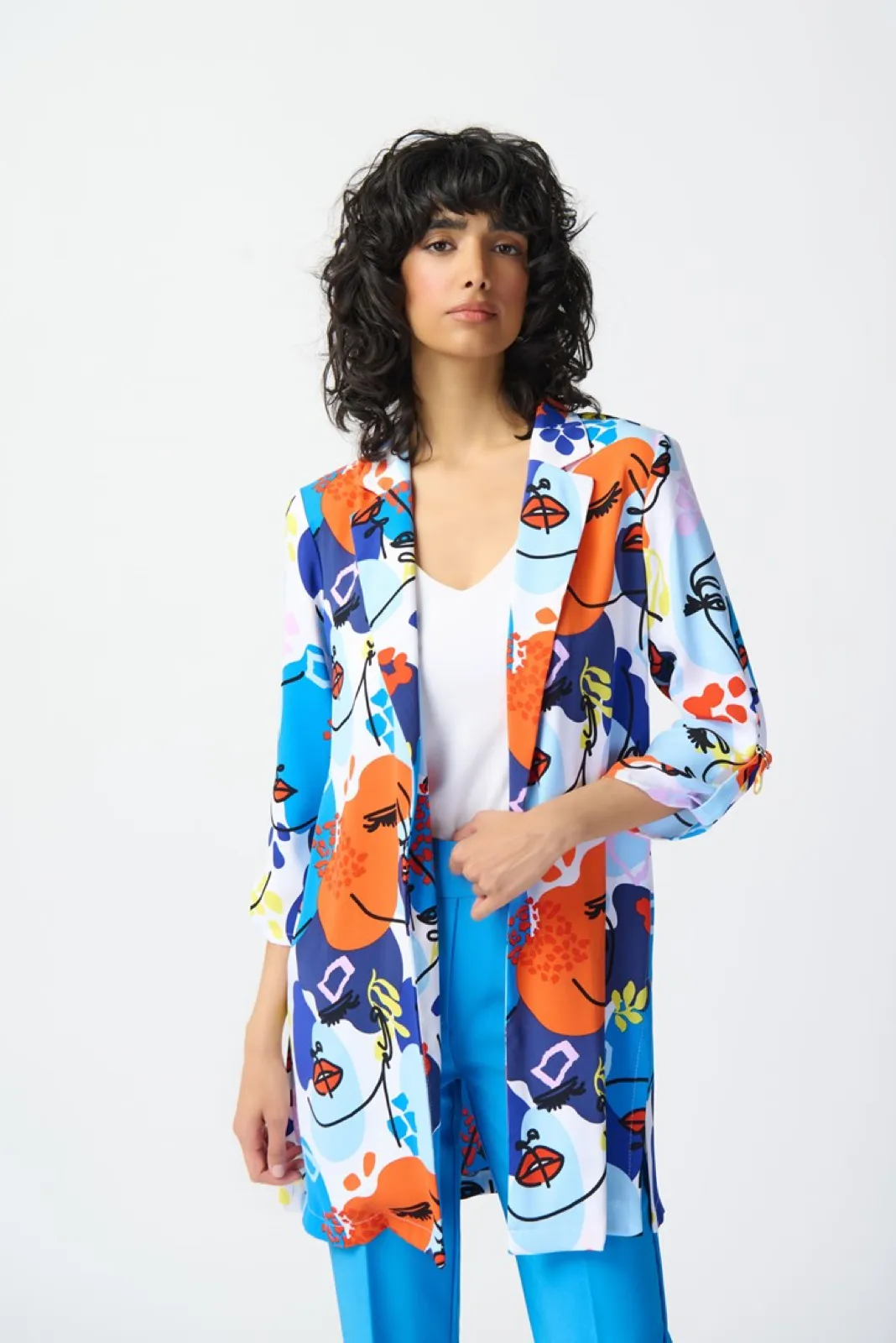 Una mujer que llevaba una Blazer estampado de caras de Joseph Ribkoff con pantalones azules.