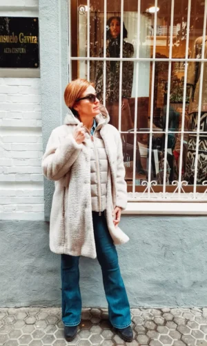 Una mujer con un Chaquetón de la firma Donjaz con interior acolchado desmontable parada frente a una tienda.