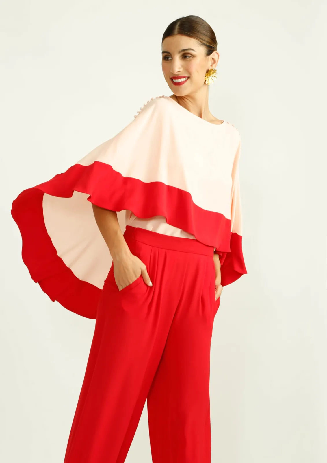 La modelo luce una blusa fluida bicolor de dos piezas Alba Conde y pantalón rojo.